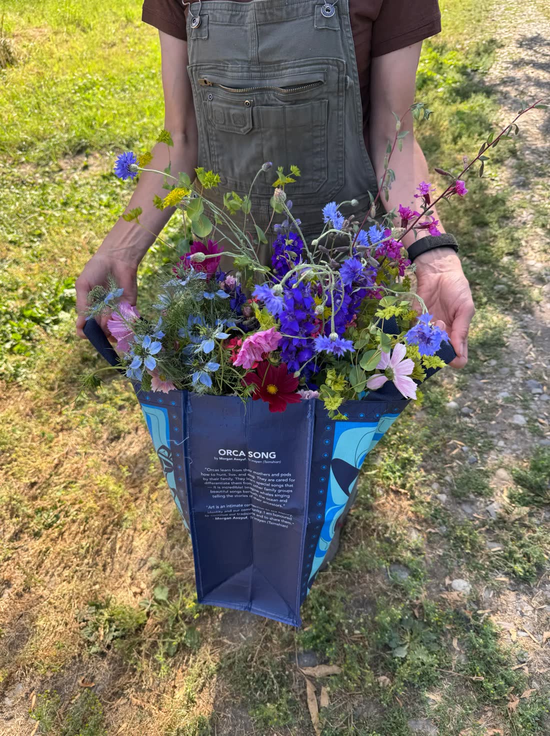 Holding a bag overflowing with freshly cut flowers