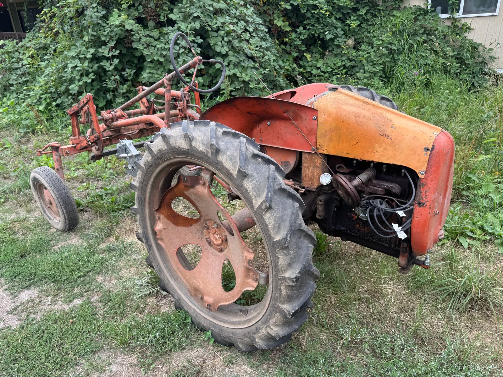 An old orange tractor resting by the hedge
